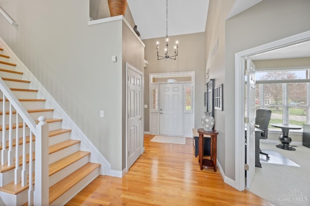 entryway featuring a high ceiling, an inviting chandelier, stairway, and light wood-style floors