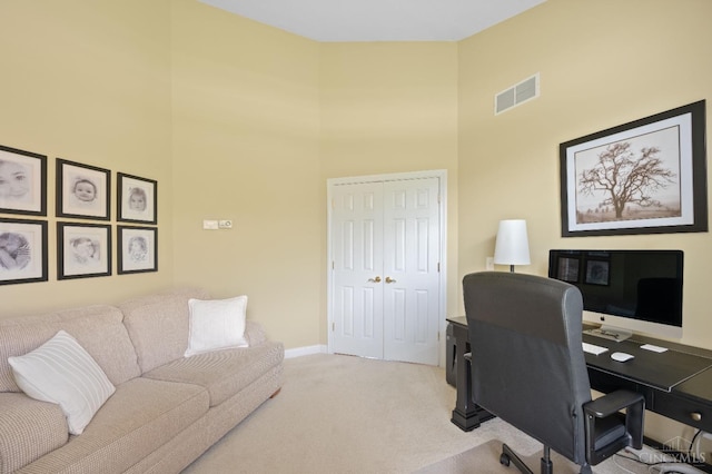 home office with baseboards, a high ceiling, light carpet, and visible vents