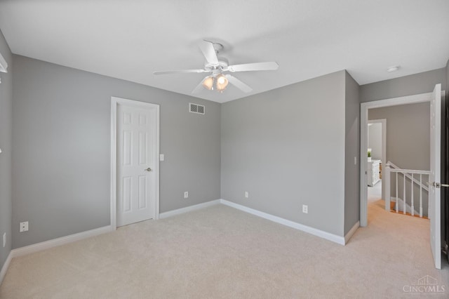 carpeted spare room featuring baseboards, ceiling fan, and visible vents