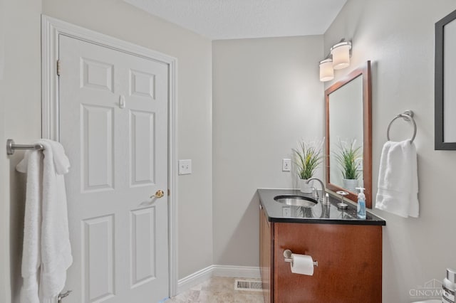 bathroom featuring a sink, double vanity, a textured ceiling, baseboards, and visible vents