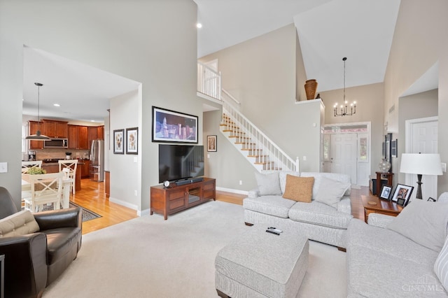 living room featuring baseboards, light wood finished floors, a high ceiling, and stairway