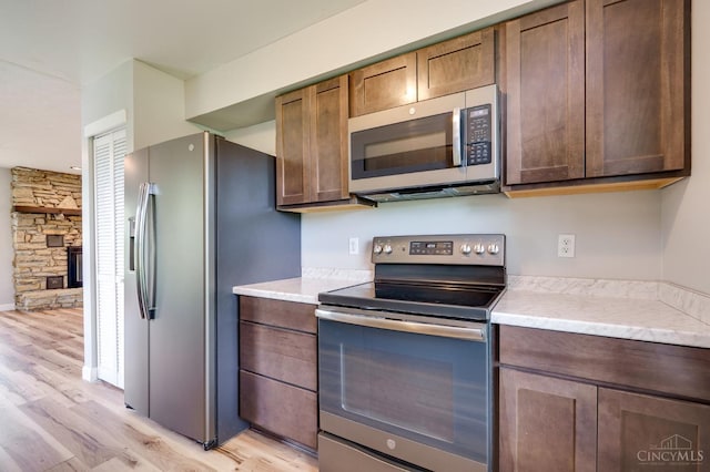 5172 Sheits Rd, Colerain Twp, OH 45251 - kitchen featuring stainless steel appliances, light wood-style floors, light countertops, and a fireplace