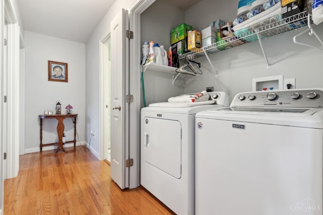 washroom featuring independent washer and dryer, laundry area, baseboards, and light wood-style flooring
