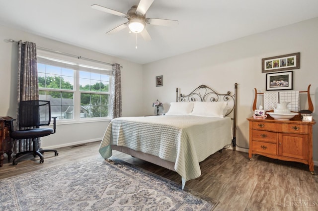 bedroom with baseboards, a ceiling fan, wood finished floors, and visible vents
