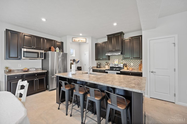 10522 Atterbury Dr, Crosby Twp, OH 45030 - kitchen with stainless steel appliances, under cabinet range hood, a sink, light countertops, and a breakfast bar area
