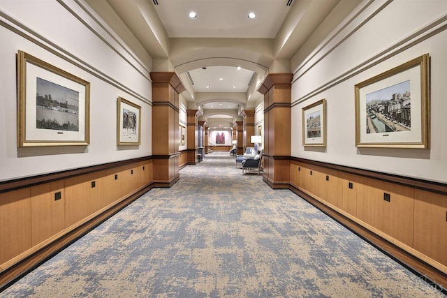 hallway with ornate columns, a decorative wall, arched walkways, recessed lighting, and carpet floors