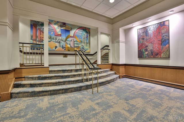 community lobby with stairs, a wainscoted wall, and recessed lighting