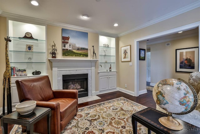 living area featuring dark wood-type flooring, a high end fireplace, crown molding, baseboards, and recessed lighting
