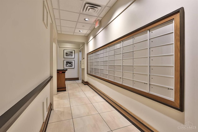 hall with mail area, light tile patterned floors, a paneled ceiling, and recessed lighting