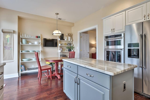kitchen featuring stainless steel appliances, dark wood-style flooring, white cabinetry, light stone counters, and pendant lighting