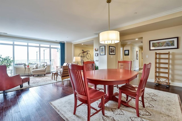dining room featuring wood finished floors, ornamental molding, and baseboards