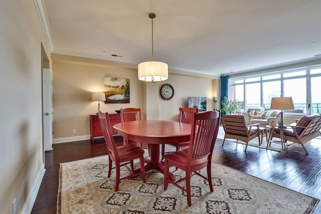 dining room with wood finished floors, crown molding, and baseboards