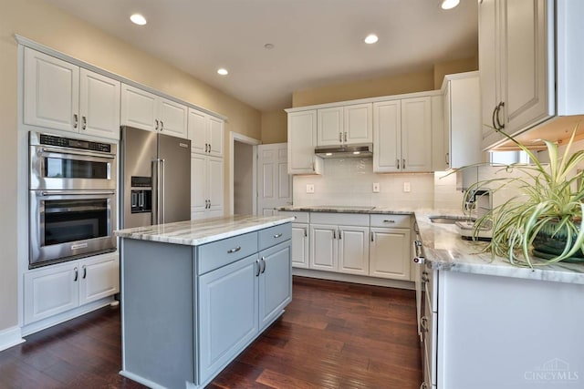 kitchen with stainless steel appliances, under cabinet range hood, white cabinets, recessed lighting, and dark wood finished floors