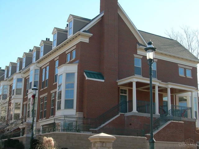 view of property exterior with stairway, brick siding, and a porch