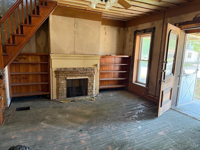 unfurnished living room featuring stairs, a stone fireplace, a ceiling fan, and visible vents