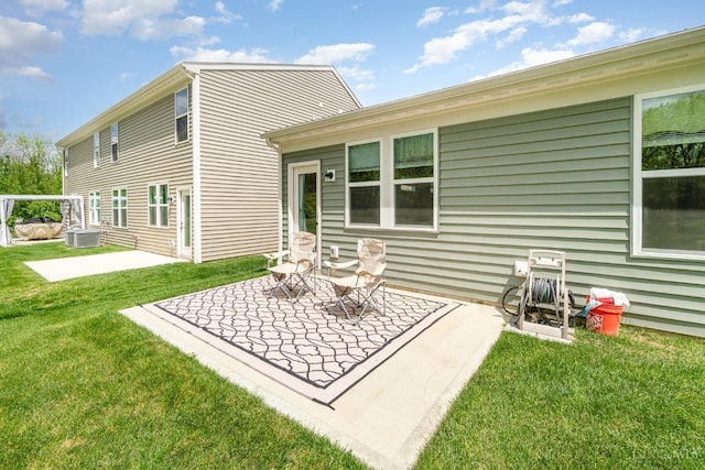 back of property with central AC unit, a patio area, and a lawn