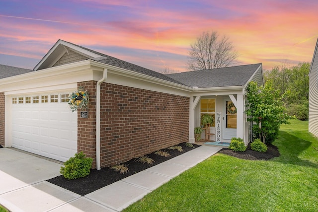 ranch-style house with roof with shingles, brick siding, driveway, a yard, and a garage