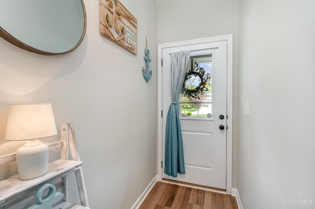 doorway with baseboards and wood finished floors