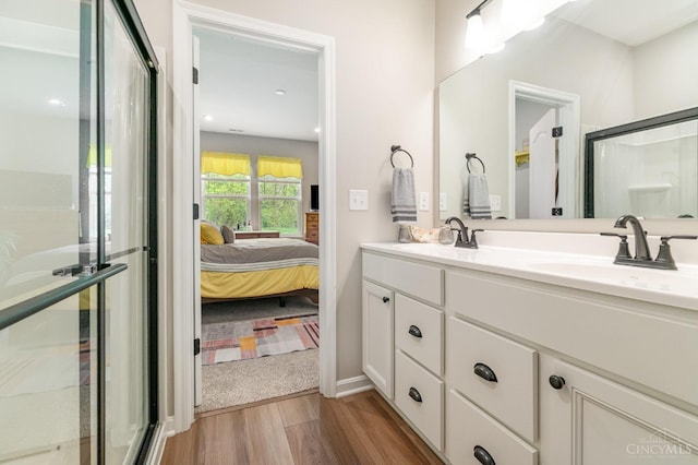 bathroom with ensuite bathroom, double vanity, a sink, and wood finished floors