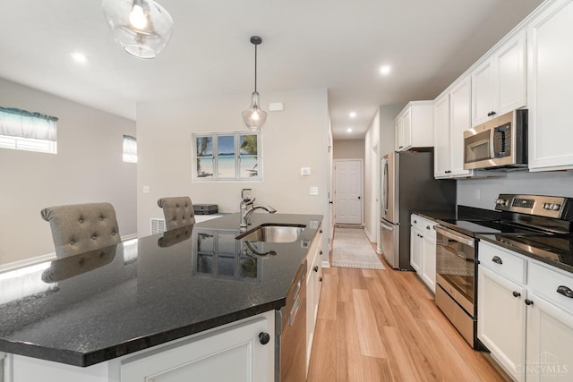 kitchen with light wood-style flooring, recessed lighting, white cabinetry, stainless steel appliances, and an island with sink