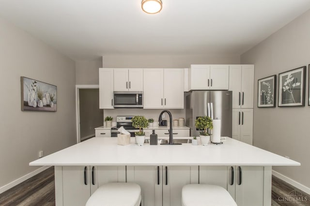 kitchen with stainless steel appliances, baseboards, dark wood-style floors, and a sink