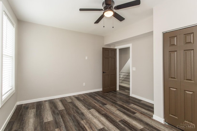 unfurnished bedroom featuring a closet, dark wood finished floors, baseboards, and ceiling fan