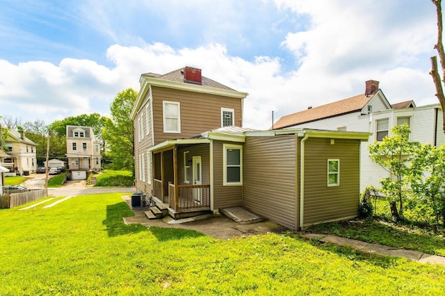 back of property featuring cooling unit and a lawn