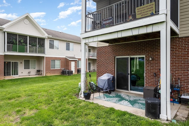 rear view of house with brick siding, a lawn, a patio area, and cooling unit