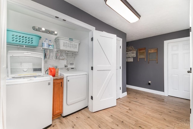 clothes washing area featuring washing machine and dryer, light wood finished floors, cabinet space, and baseboards