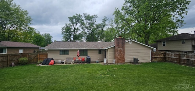 back of house featuring a fenced backyard, central AC, a chimney, and a lawn