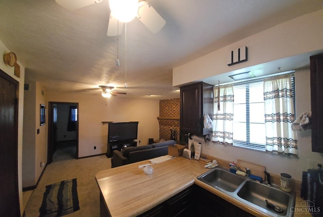 kitchen featuring a peninsula, a ceiling fan, a sink, open floor plan, and light carpet