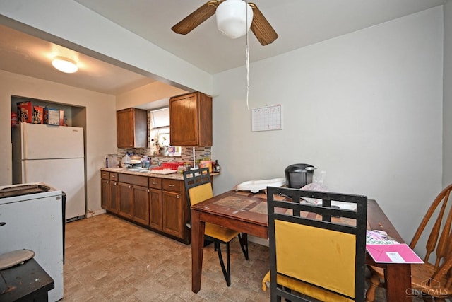 6014 Argus Rd, Cincinnati, OH 45224 - kitchen with freestanding refrigerator, a ceiling fan, stone finish floors, light countertops, and brown cabinetry