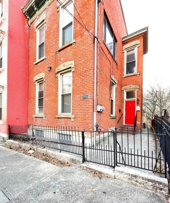 2259 Loth St, Cincinnati, OH 45219 - view of side of property with brick siding and a fenced front yard