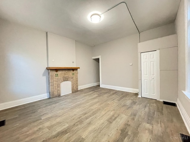 2259 Loth St, Cincinnati, OH 45219 - unfurnished living room featuring wood finished floors, baseboards, and a tiled fireplace