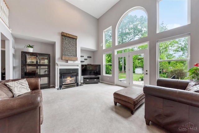 carpeted living area with a towering ceiling, a fireplace with flush hearth, and baseboards