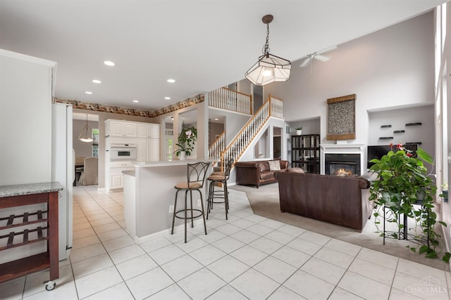 kitchen with a breakfast bar area, white appliances, light countertops, white cabinetry, and a glass covered fireplace