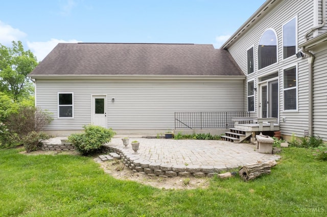 back of house featuring a patio, a lawn, and a shingled roof