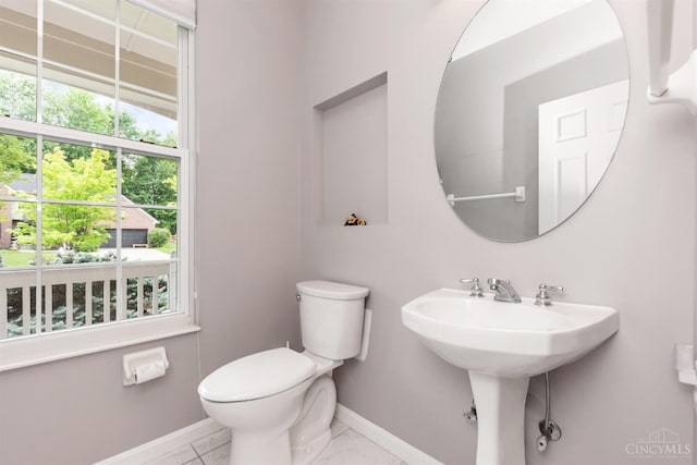 half bath featuring baseboards, toilet, and tile patterned flooring