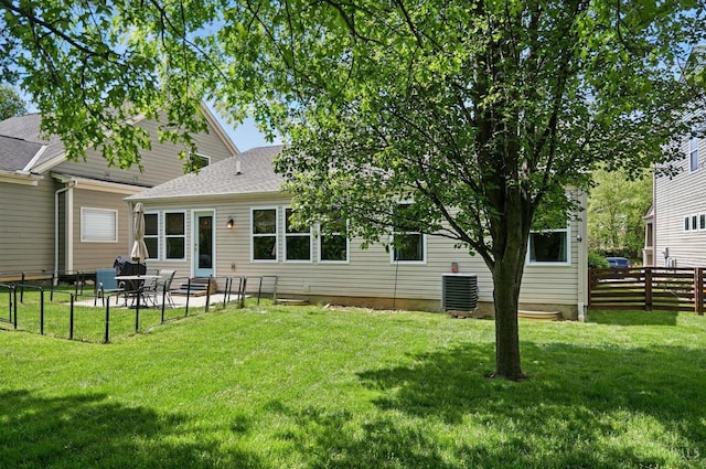 rear view of property with central air condition unit, roof with shingles, and a patio area