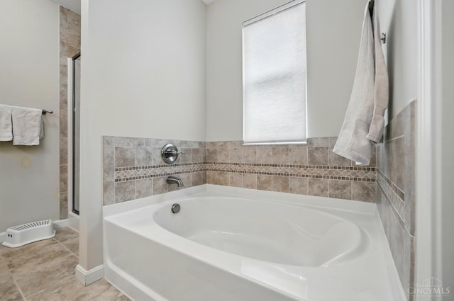 full bathroom with a bath, a shower stall, tile patterned floors, and baseboards