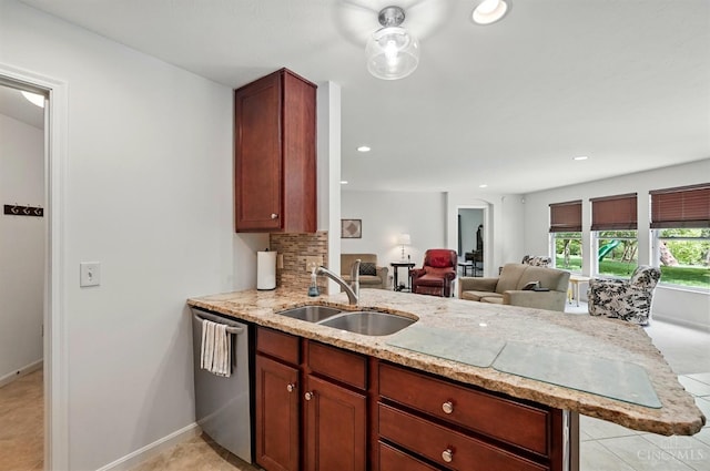 kitchen with a sink, stainless steel dishwasher, light stone countertops, a peninsula, and open floor plan