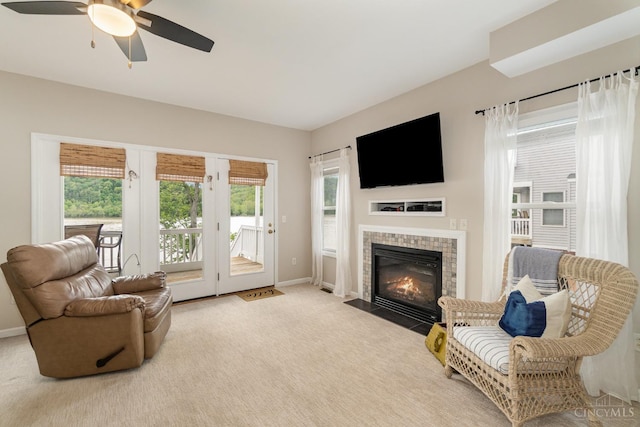 carpeted living room with baseboards, a ceiling fan, and a tile fireplace