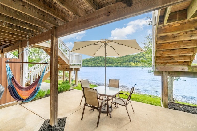 view of patio / terrace featuring stairway, a water view, and outdoor dining space