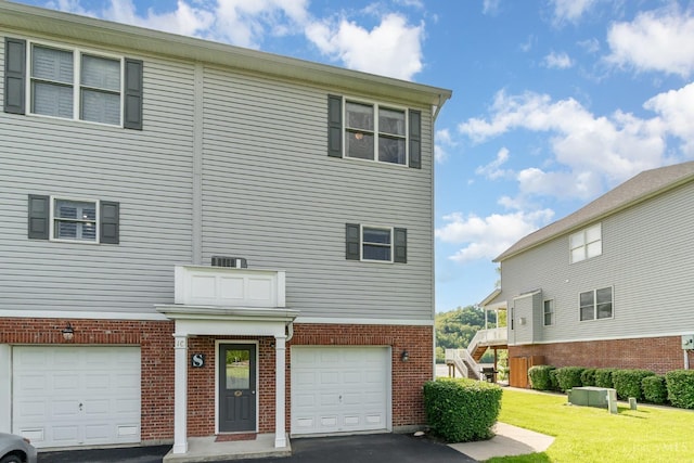 multi unit property with an attached garage, brick siding, and a front lawn
