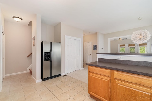 kitchen with stainless steel fridge with ice dispenser, dark countertops, light tile patterned flooring, and decorative light fixtures