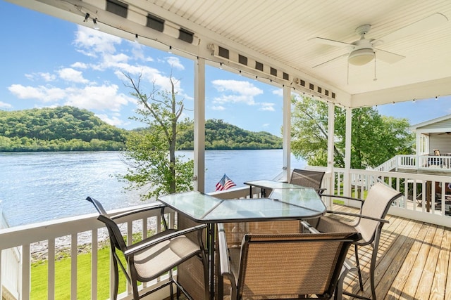 wooden terrace featuring a water view, ceiling fan, and outdoor dining area