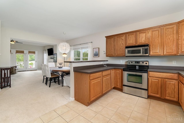 kitchen with stainless steel appliances, a peninsula, dark countertops, and plenty of natural light