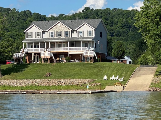 rear view of property with a water view, stairway, a lawn, and a view of trees