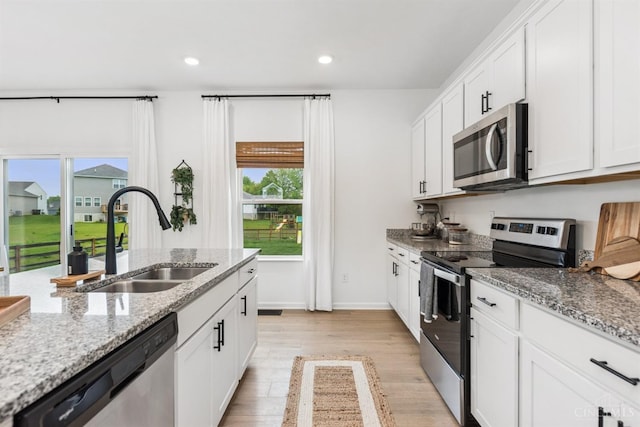1750 Parkfield Way, Goshen Twp, OH 45122 - kitchen with stainless steel appliances, a sink, light wood-style floors, white cabinetry, and baseboards
