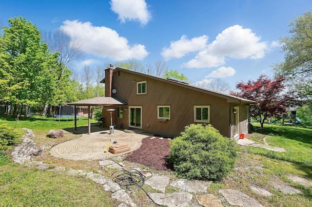 11675 New Biddinger Rd, Harrison Twp, OH 45030 - rear view of house featuring a trampoline, a patio, a chimney, and a yard